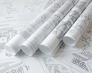 Rolled engineering blueprints and technical drawings spread on a flat surface